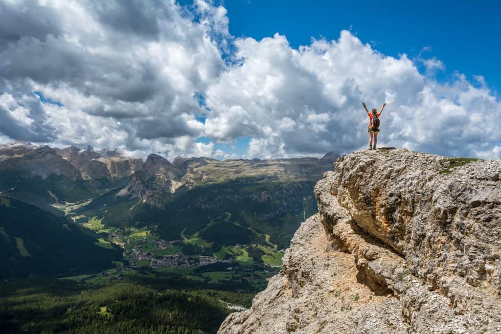 Cet homme sait comment retrouver le moral en levant les bras sur une colline devant un magnifique paysage