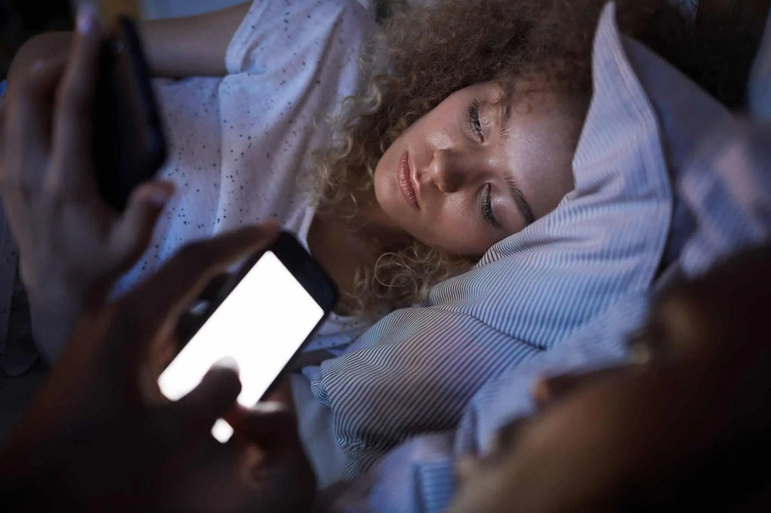 Couple au lit, éclairé par la lumière bleue de leurs smartphones