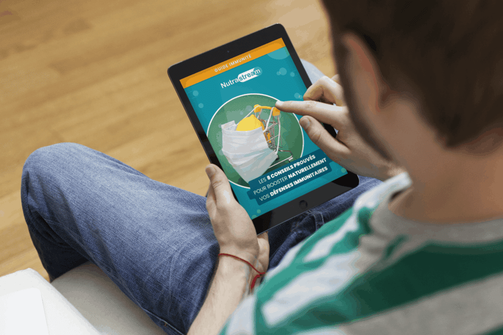 un homme consulte le Guide Immunité Nutrastream sur sa tablette dans son salon