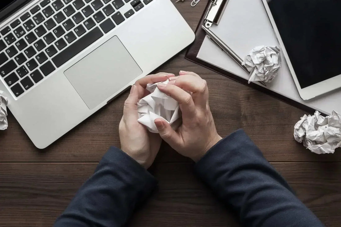 Femme stressée à cause du travail froissant du papier devant son ordinateur