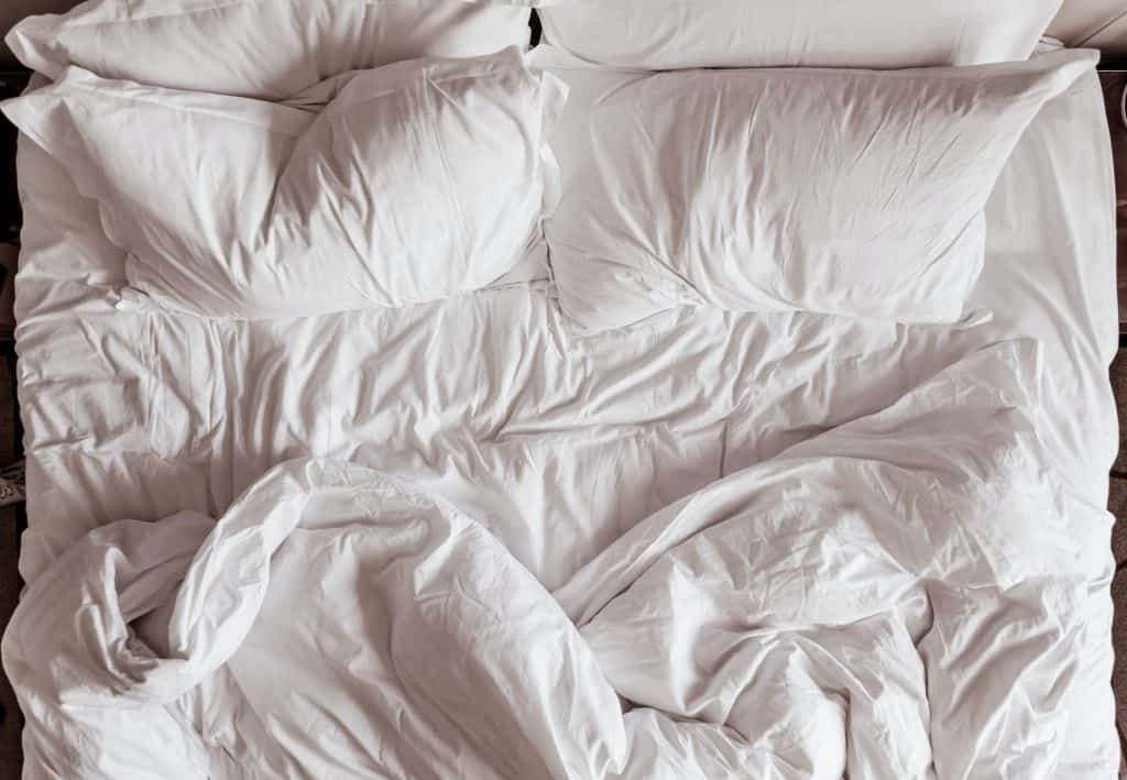 Lit défait d’une personne se posant des questions sur son temps sommeil idéal