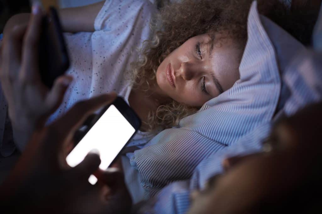 Couple au lit, éclairé par la lumière bleue de leurs smartphones