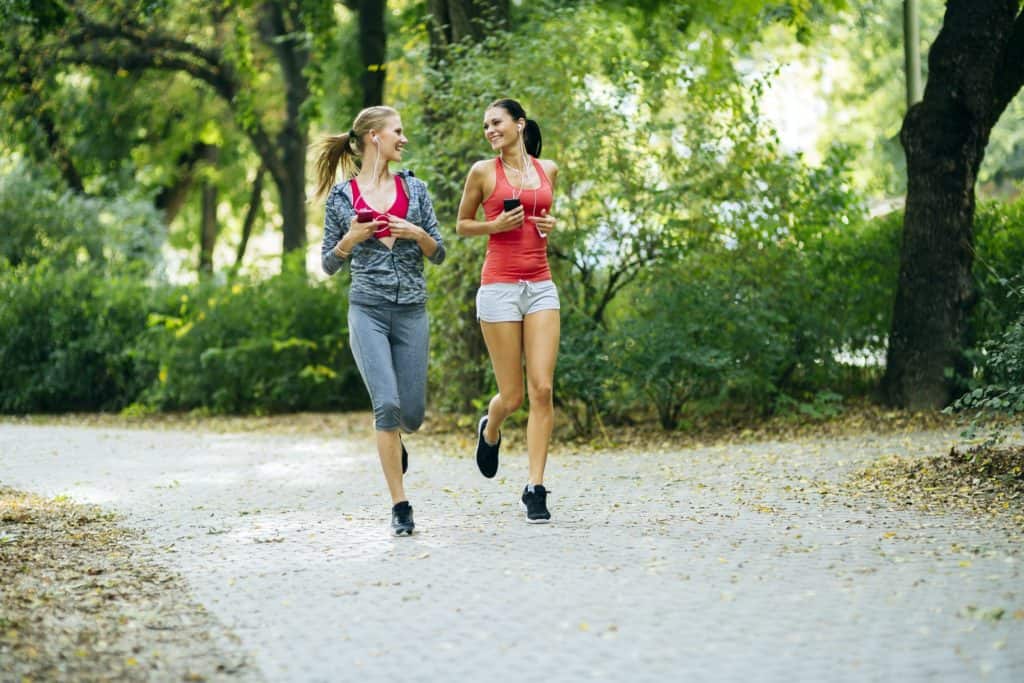 Luttez contre l'absence de vitalité comme ces deux jeunes femmes qui sont heureuses de faire leur jogging en forêt