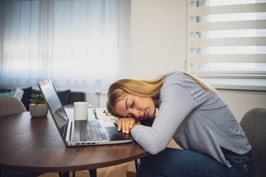 Jeune femme active dormant au travail sur son ordinateur