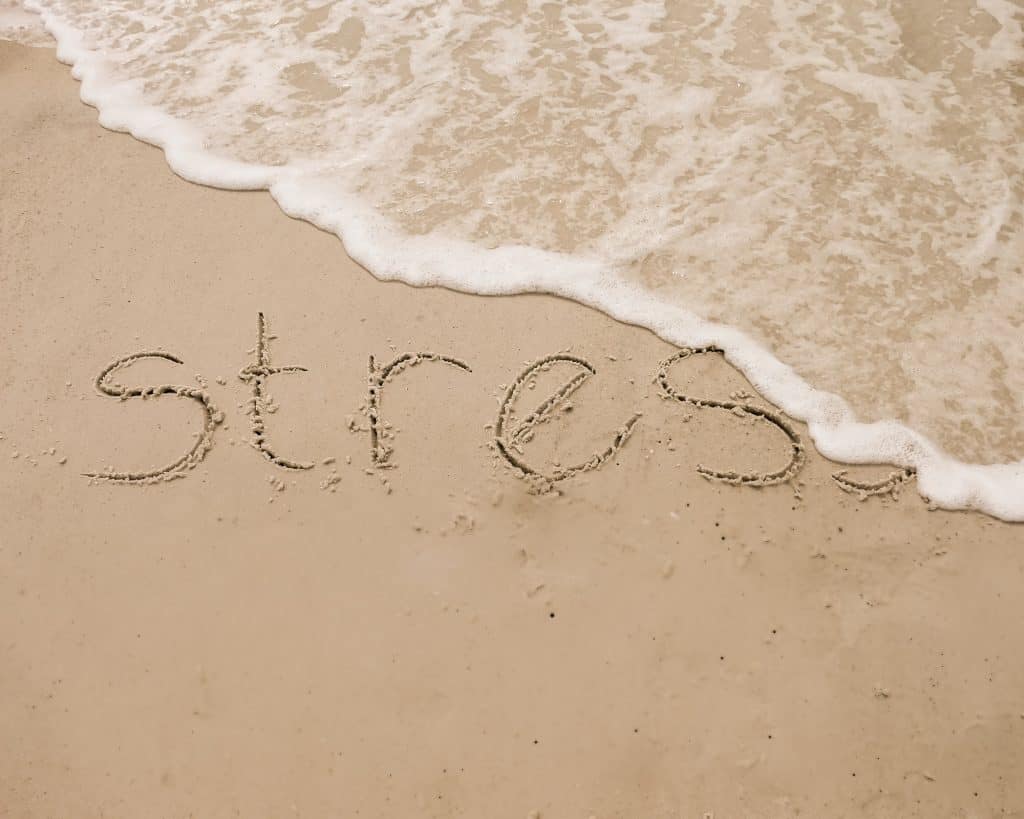 Comment gérer son stress, à l'image de cette vague qui efface le mot stress écrit sur le sable d'une plage